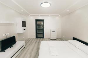 a white bedroom with a bed and a tv at Rika apartments in Chernivtsi