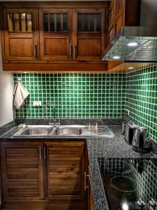 Khanom Sea Breeze apartment في خانوم: مطبخ مع حوض وجدار أخضر من البلاط