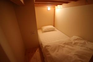 a small room with a white bed in it at Running Bare in Fuji