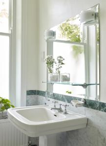 a white bathroom with a sink and a mirror at Mountview Guesthouse Crouch End in London