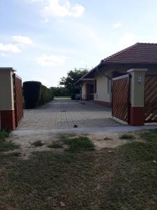 a house with a gate and a brick driveway at Bella Vendégház Mórahalom in Mórahalom