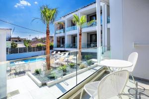a balcony with a table and chairs and palm trees at Senso Suites in Nea Peramos
