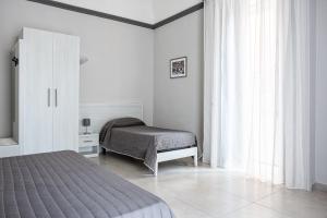 una camera bianca con letto, armadio e finestra di Hotel Costanza a Catania