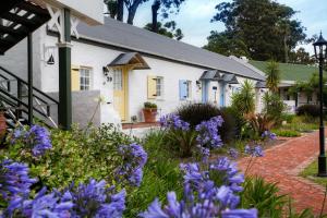 a house with a flower garden in front of it at Tsitsikamma Village Inn in Stormsrivier