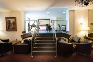 a lobby with a staircase with chairs and a table at Whitewater Hotel & Spa in Newby Bridge