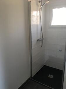 La salle de bains est pourvue d'une douche avec une porte en verre. dans l'établissement TANTE LICHE, à Penmarcʼh