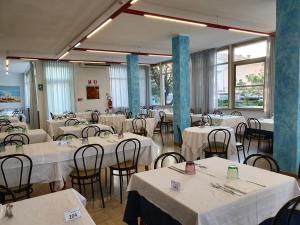 a room filled with tables and chairs with white table linen at Hotel Bristol - Koolibry Hotels in Cervia