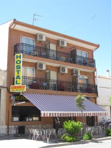 a building with a balcony and tables and chairs at Hostal Gastrobar Carmelo in Villarejo de Salvanés