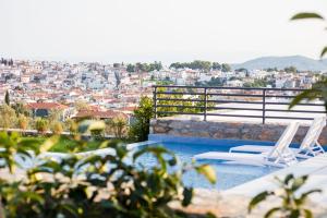 a pool with two chairs and a view of a city at Amira in Skiathos