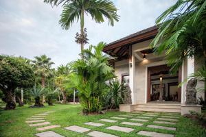 a house with palm trees and a walkway at Baan Pinya Balinese Style Pool Villa in Krabi town