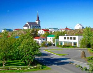 una ciudad con una iglesia en lo alto de una colina en Lundur and Klettur, en Borgarnes