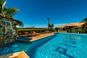 a swimming pool with two chairs and a house at Pousada Piuval in Poconé