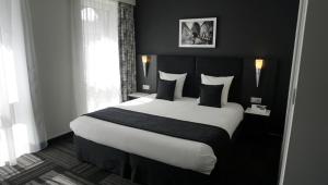 
a white bed with a white comforter and pillows at Hotel Saint Daniel in Péruwelz
