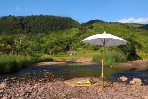 a beach with an umbrella and a chair in a river at ต้นน้ำน่าน บ่อเกลือ in Ban Sale