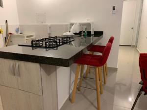 a kitchen with a stove and some red chairs at Apartamento - Tocaima in Tocaima