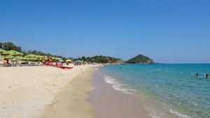 a beach with umbrellas and people in the water at Villetta Fiori in Castiadas