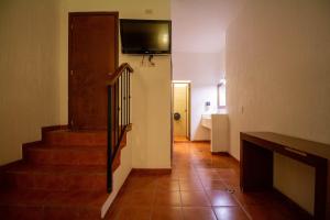 un couloir avec un escalier et une télévision murale dans l'établissement Hotel Degollado, à Degollado