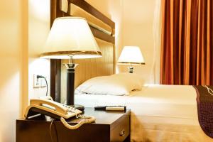 洛美Bravia Eco Hotel Lome的酒店客房配有电话和床。
