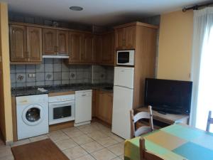 a kitchen with wooden cabinets and white appliances and a table at Apartamentos Solans in Bielsa