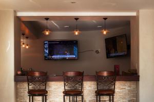 un bar con 3 sillas y TV en la pared en Hotel Calacoto, en La Paz