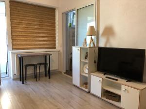 uma sala de estar com uma televisão de ecrã plano e uma mesa em Cozy Place 47-Self check in & out-HBO MAX em Piteşti
