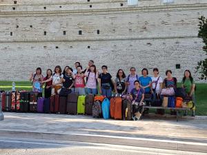 um grupo de pessoas sentadas num banco com bagagem em Domus Pacis Santa Chiara casa per ferie em Loreto