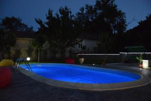 a large blue swimming pool in a yard at night at Guest House Raiski Kаt in Mezek