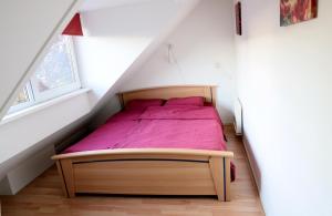 a bedroom with a bed with pink sheets in a attic at Vakantievilla Markant in Balk
