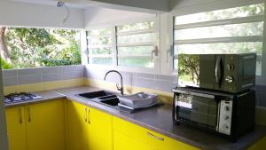 a kitchen with yellow cabinets and a microwave at PERLE CRÉOLE in Sainte-Anne