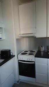 a kitchen with a stove and white cabinets at Pikkukoti Ukki in Keuruu