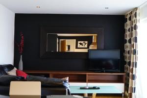 a living room with a black wall and a mirror at Hullidays - The Sawmill Suite in Hull