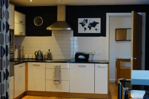 a kitchen with white cabinets and a black wall at Hullidays - The Sawmill Suite in Hull