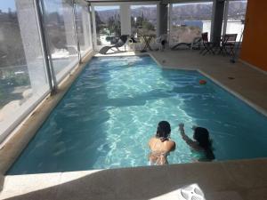 two women in a swimming pool in a building at Refugio Playa Perelli in Villa Carlos Paz