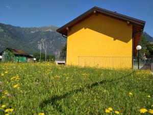 a yellow building in a field of flowers at Casa Vacanze Le Casette in Masera