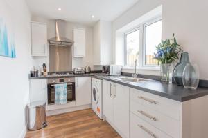 a kitchen with white cabinets and a sink at Rana Court Apts 1 & 2 Bed Apts close to Hospitals Business & Science Parks in Oxford