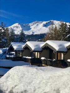 a house covered in snow with mountains in the background at Rue de Bel-Aube Chalet Joli 10 in Crans-Montana