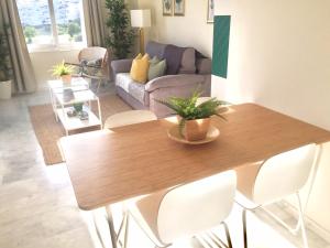 sala de estar con mesa de madera y sillas blancas en Valle Romano golf resort Capitolio Estepona, en Estepona