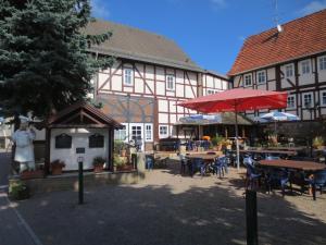 a building with tables and umbrellas in a courtyard at Hotel-Restaurant Johanneshof in Nentershausen