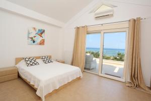 a bedroom with a bed and a balcony with the ocean at Villa The View - Beachfront, 5 Bedrooms, BBQ, View in Pefkohori