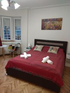 a bedroom with a bed with red sheets and pillows at Bohemian Dawn Apartment in Belgrade