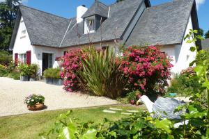 a white house with pink flowers in the yard at Le Diamant in Le Minihic-sur-Rance