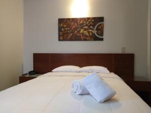 a bed with two white towels on top of it at Hotel Sumaq Inn Sac in Lima