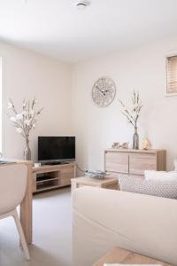 sala de estar blanca con TV y sofá en Santvort Luxury Apartment with Private Parking, en Zandvoort