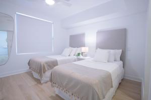 two beds in a room with white walls and wood floors at Mullins Grove in Saint Peter