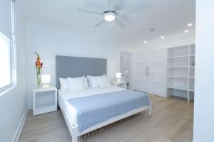 a white bedroom with a white bed and a ceiling fan at Mullins Grove in Saint Peter