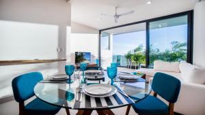 a dining room with a glass table and blue chairs at Family Apartments Near Beach Polo88 in Playa del Carmen
