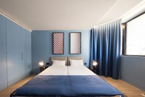 - une chambre avec un grand lit aux murs bleus dans l'établissement BessaApartments, à Porto