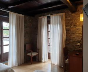 1 dormitorio con cortinas blancas y ventana en Hotel Mirador de Barcia, en Ribeira de Piquin