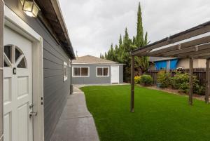 a backyard with green grass and a white door at @ Marbella Lane 5BR House in Downtown Redwood City in Redwood City