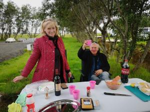 una mujer de pie junto a una mesa con una botella de vino en Iceland Igloo Village, en Hella